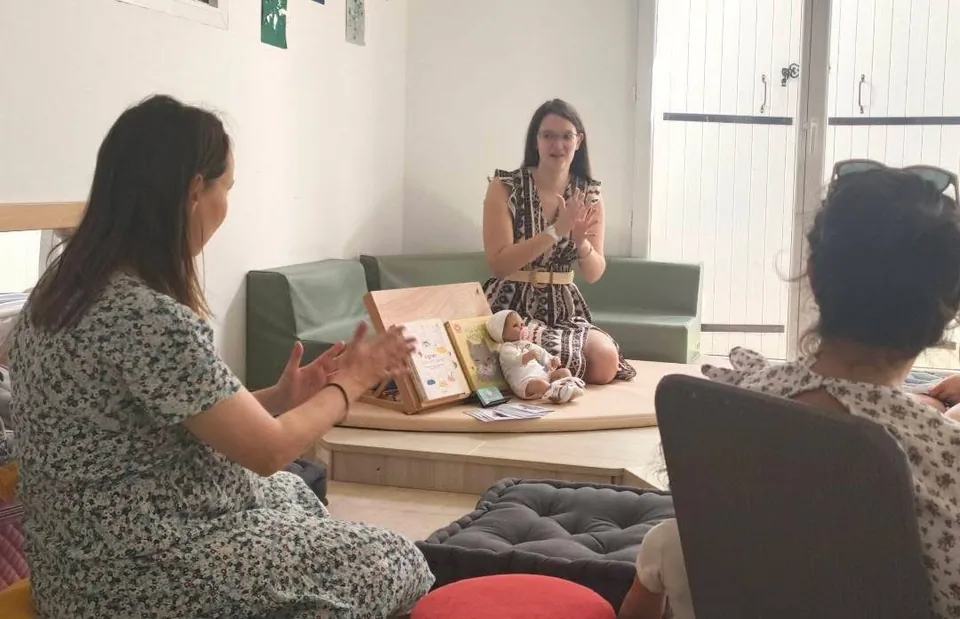 L'animatrice signe une comptine devant des parents, assis en cercle.